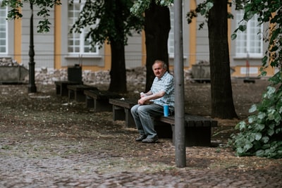 一个穿着蓝色衬衫的男人白天坐在棕色的木凳上